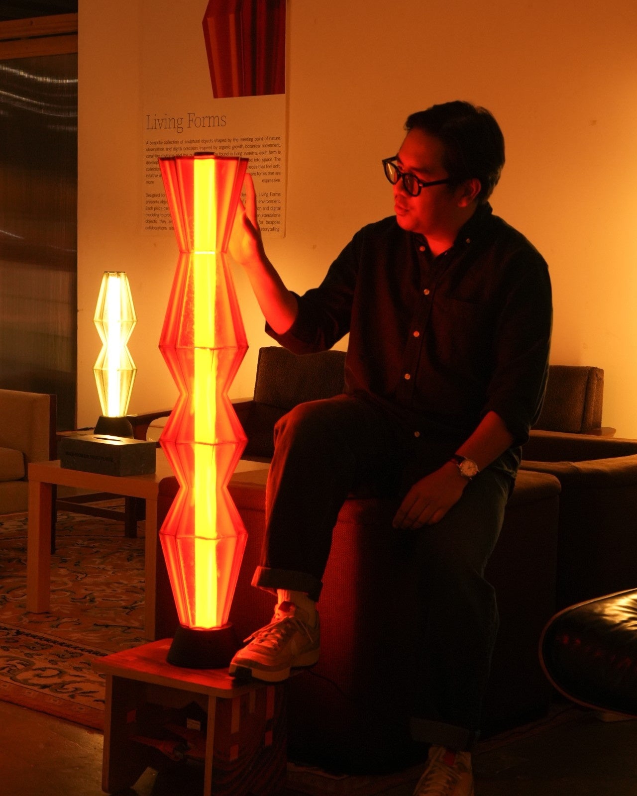 Person interacting with a glowing orange 3D printed lamp in an indoor setting