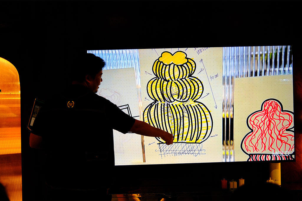 Person pointing at a screen displaying a design of a 3D printed lamp.