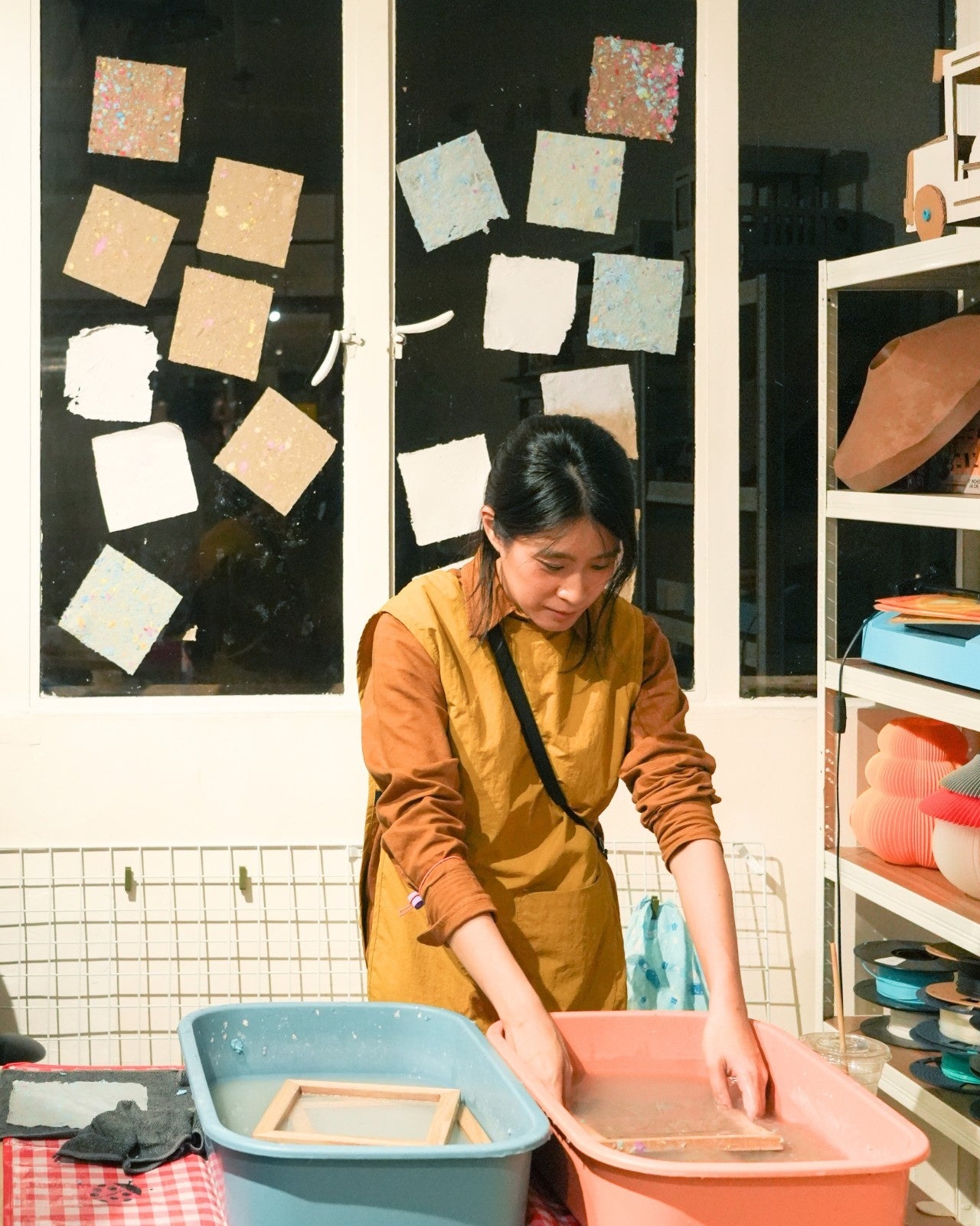 Person in a yellow apron working with containers in a workshop setting