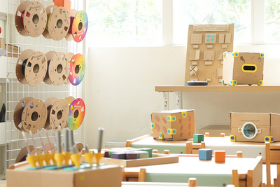 Children's playroom with educational toys and cardboard structures.